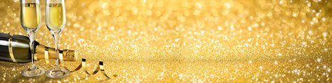 To glas med mousserende vin står på et glitrende gyldent bord ved siden af en åbnet champagneflaske. Der er også banderoller og en festlig atmosfære, der symboliserer fejring.